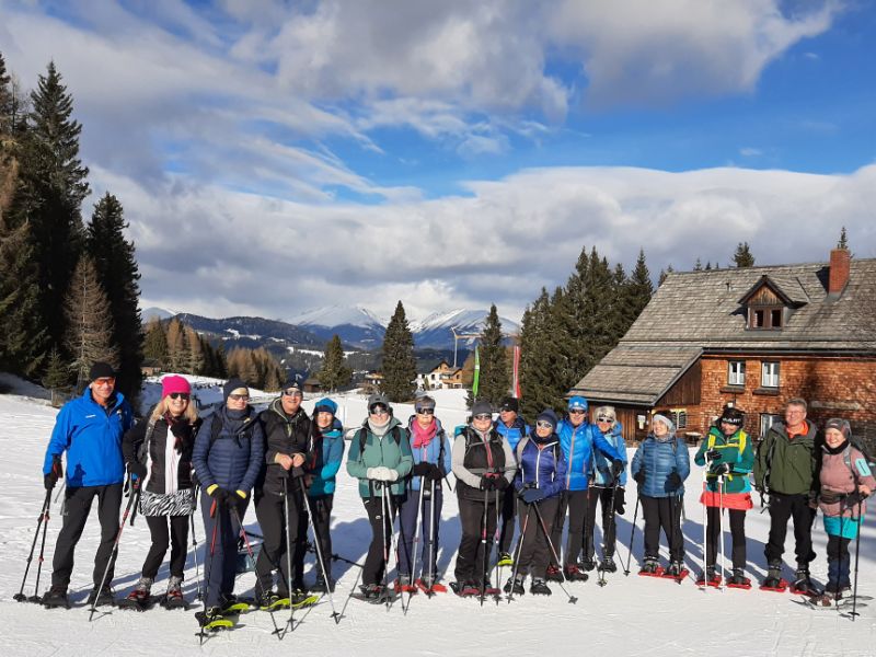Schneeschuhwandergruppe vor einer Almhütte