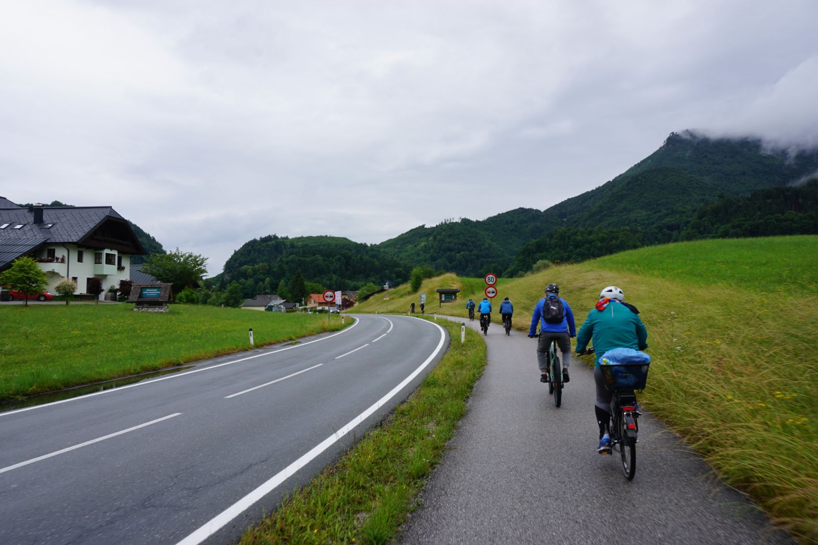 Zwei Radfahrer auf einem Radweg vor grünen Bergen
